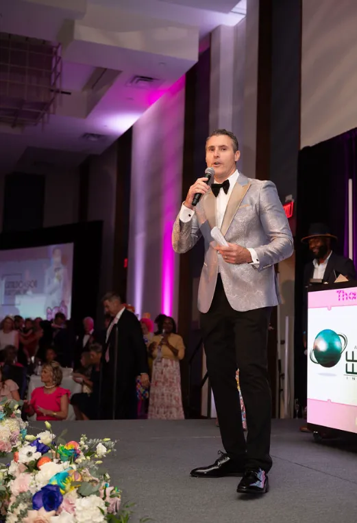 Steve Grandizio holding a microphone on stage during a live auction